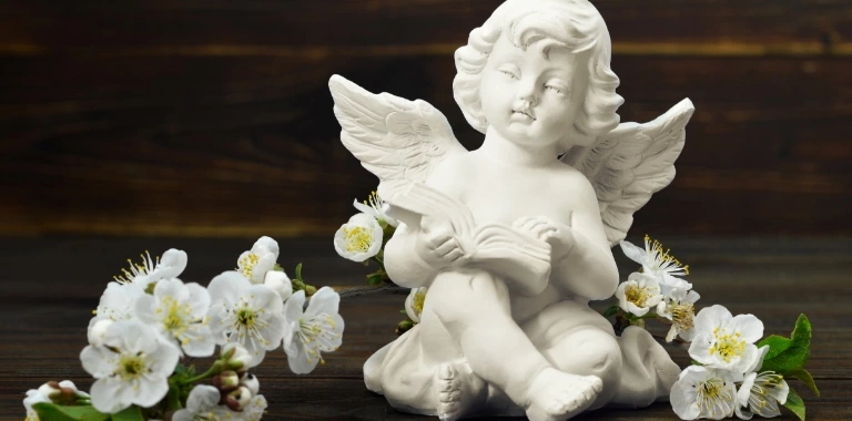 Figurka anioła oraz białe kwiaty